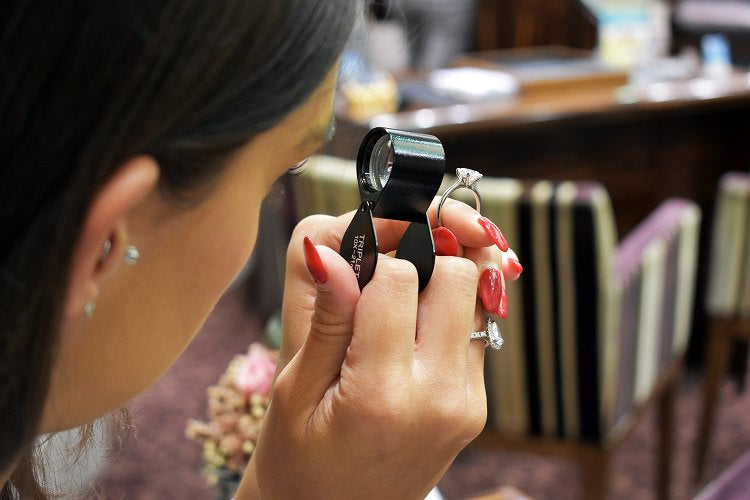 A woman Examining an engagement ring checking the clarity of a solitaire diamond engagement ring