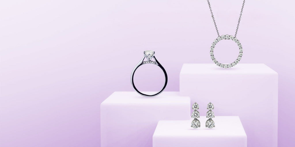 A solitaire round diamond engagement ring, diamond pendant and diamond earrings on display