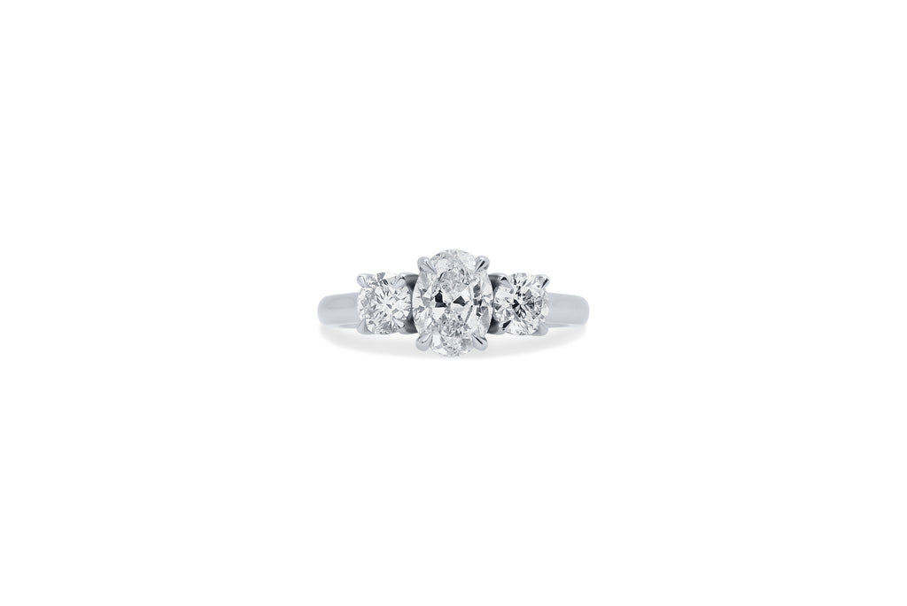 A custom-made trilogy diamond engagement ring with an oval shaped diamond at the centre and round diamond shoulders