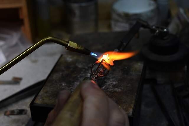 An engagement ring getting repaired through the use of a blow torch in a repair shop
